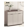 Narrow beige shoe cabinet with upper drawers beside a plant