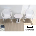 White woven-look chairs and round side table beside a window