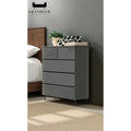 Dark grey drawer chest beside a bed