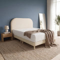 Cream Sorella bed with rounded headboard against a blue wall