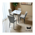 Square white dining table with grey chairs beside a window