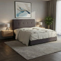 Dark button-tufted bed beside a bedside lamp